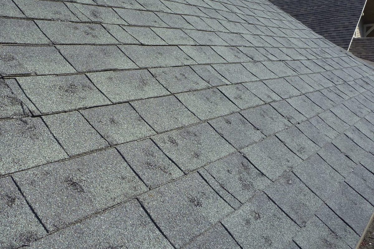 Insurance adjuster and roofing contractor inspecting hail damage together on a Kansas City roof
